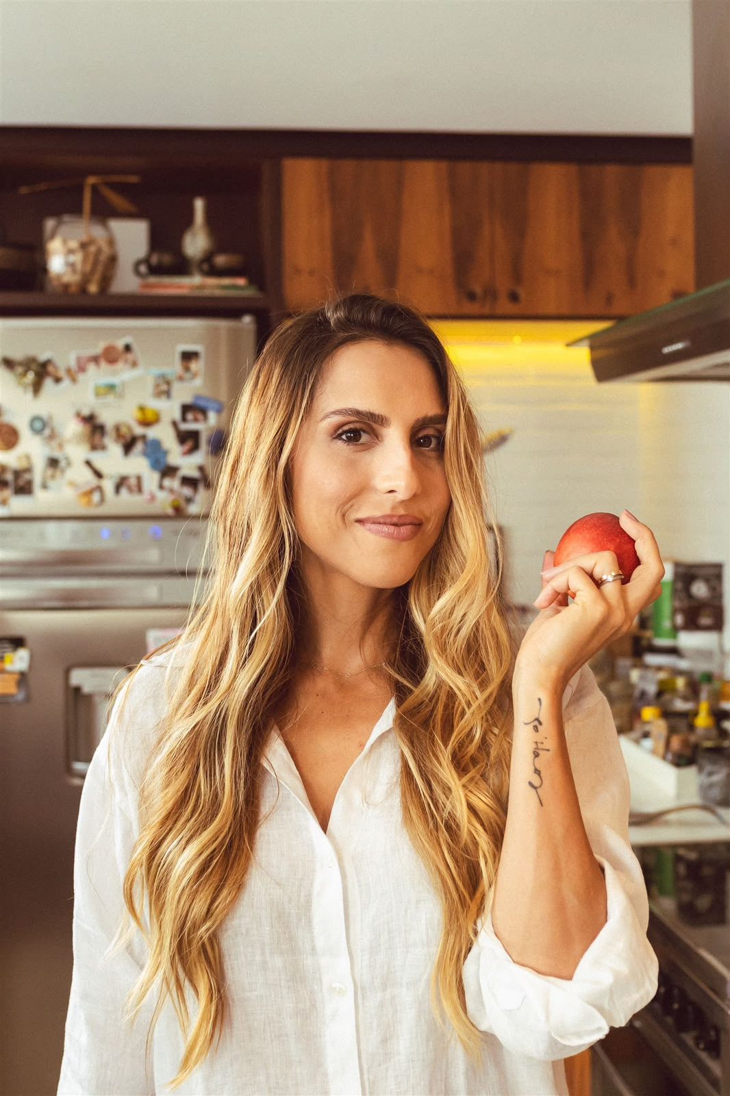 Xanda Fogaça na cozinha, segurando uma fruta